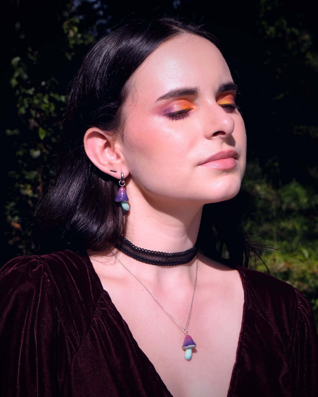 Charms faits main en forme de champignons bleus et violets, portés par un modèle féminin en pendentif et boucle d'oreille.