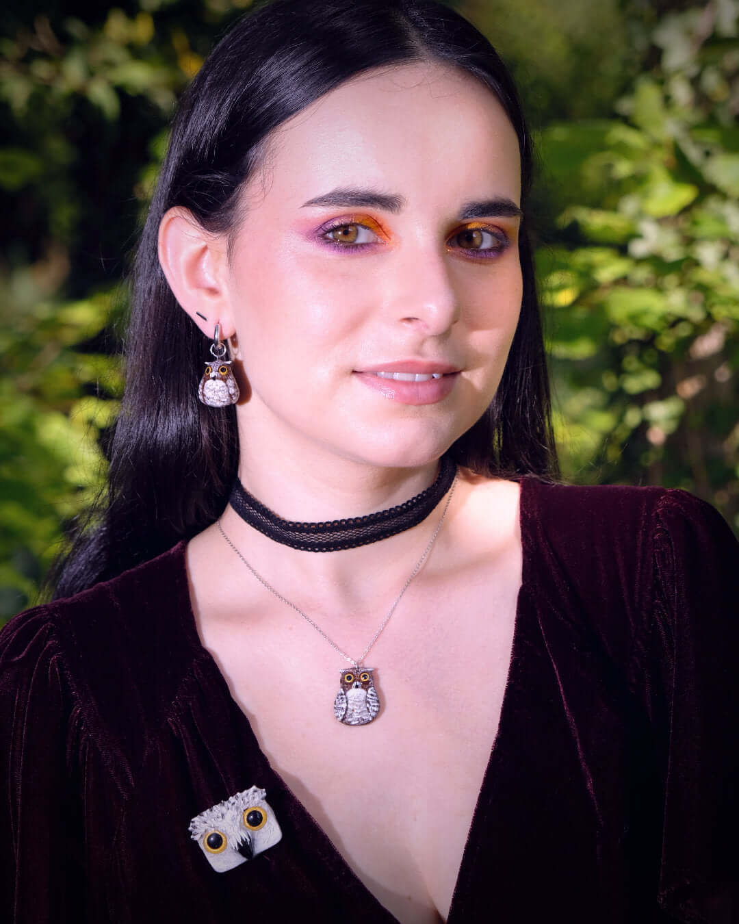 Pendentif et boucle d'oreille en forme de hibou brun, portés par un modèle féminin.
