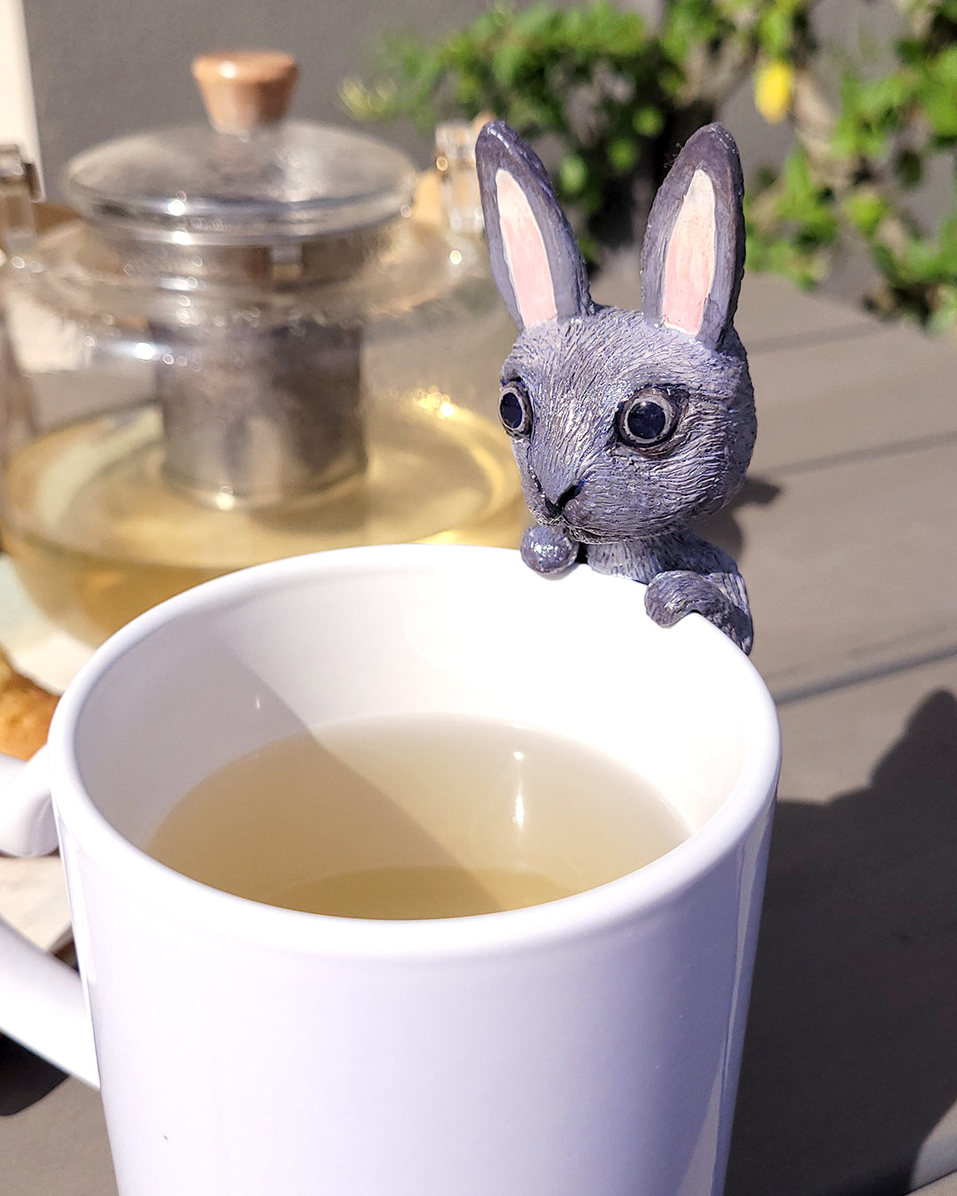 Mini figurine en forme de lapin gris accrochée à une tasse de thé vert