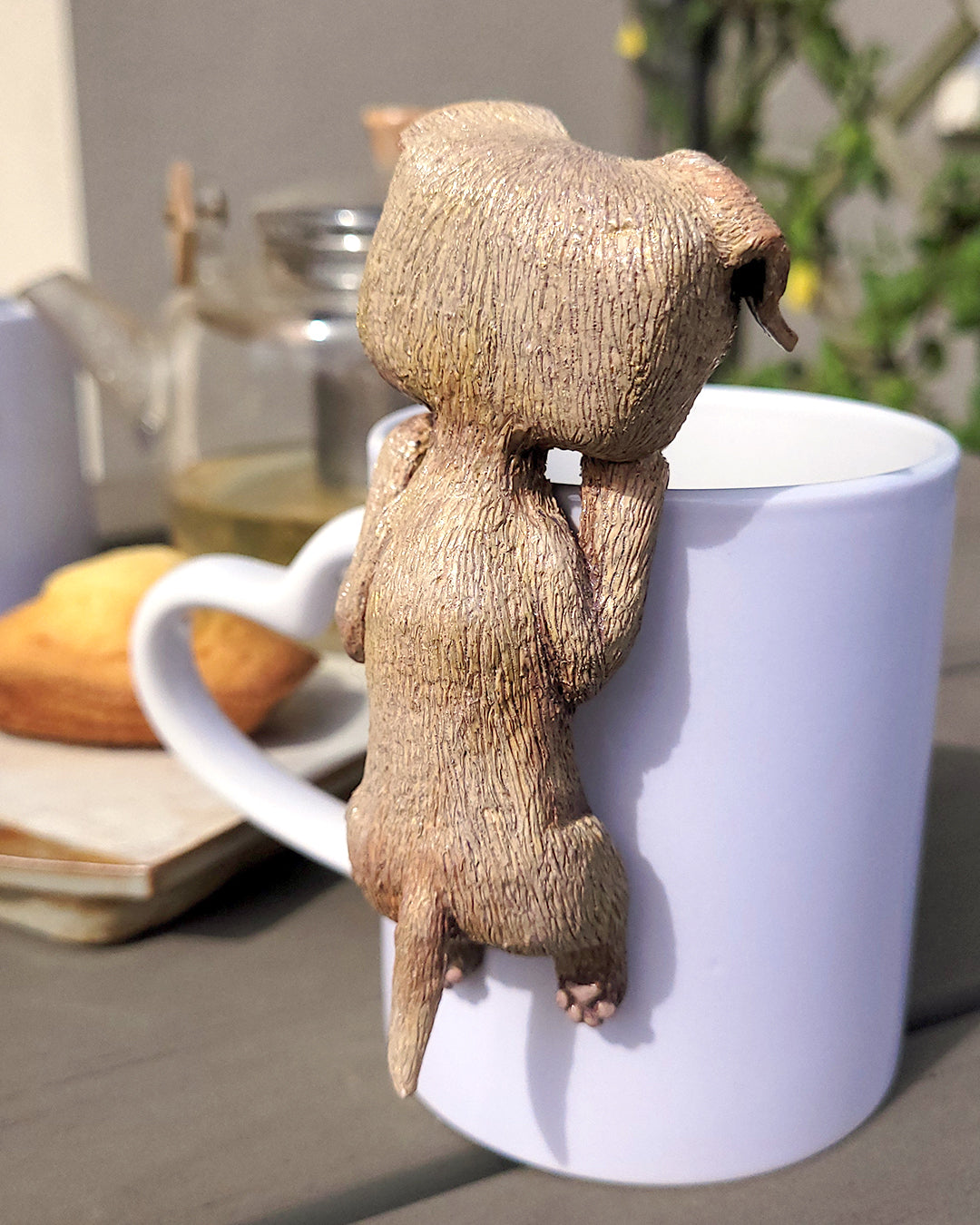 Mini figurine en forme de labrador accrochée à une tasse de thé vert, accompagné de madeleines