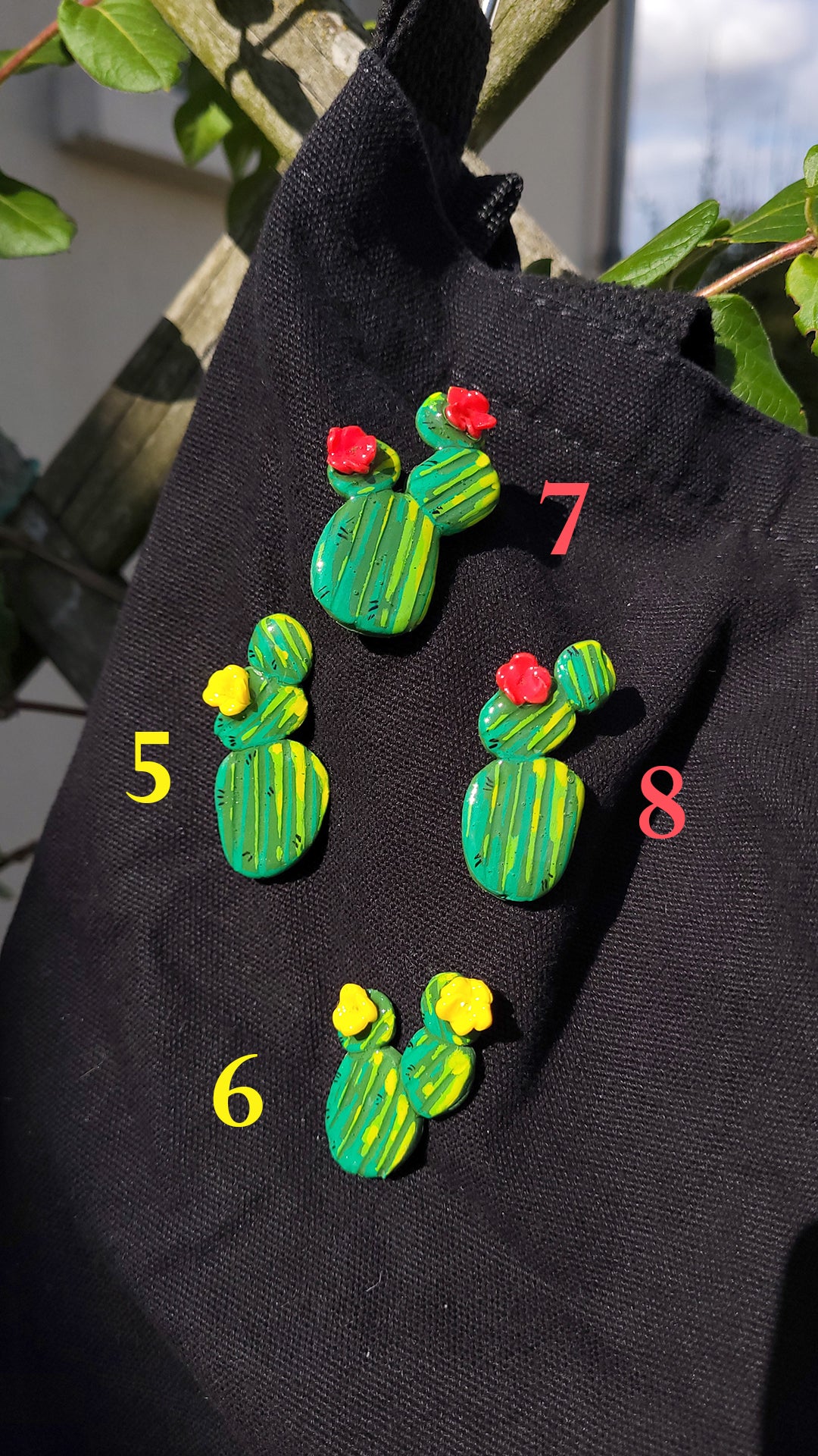 4 pins en forme de cactus avec des fleurs jaunes ou rouges accrochés sur un tote bag