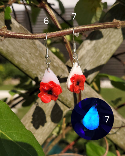 2 boucles d'oreilles ornées de coquelicot accrochées à une plante