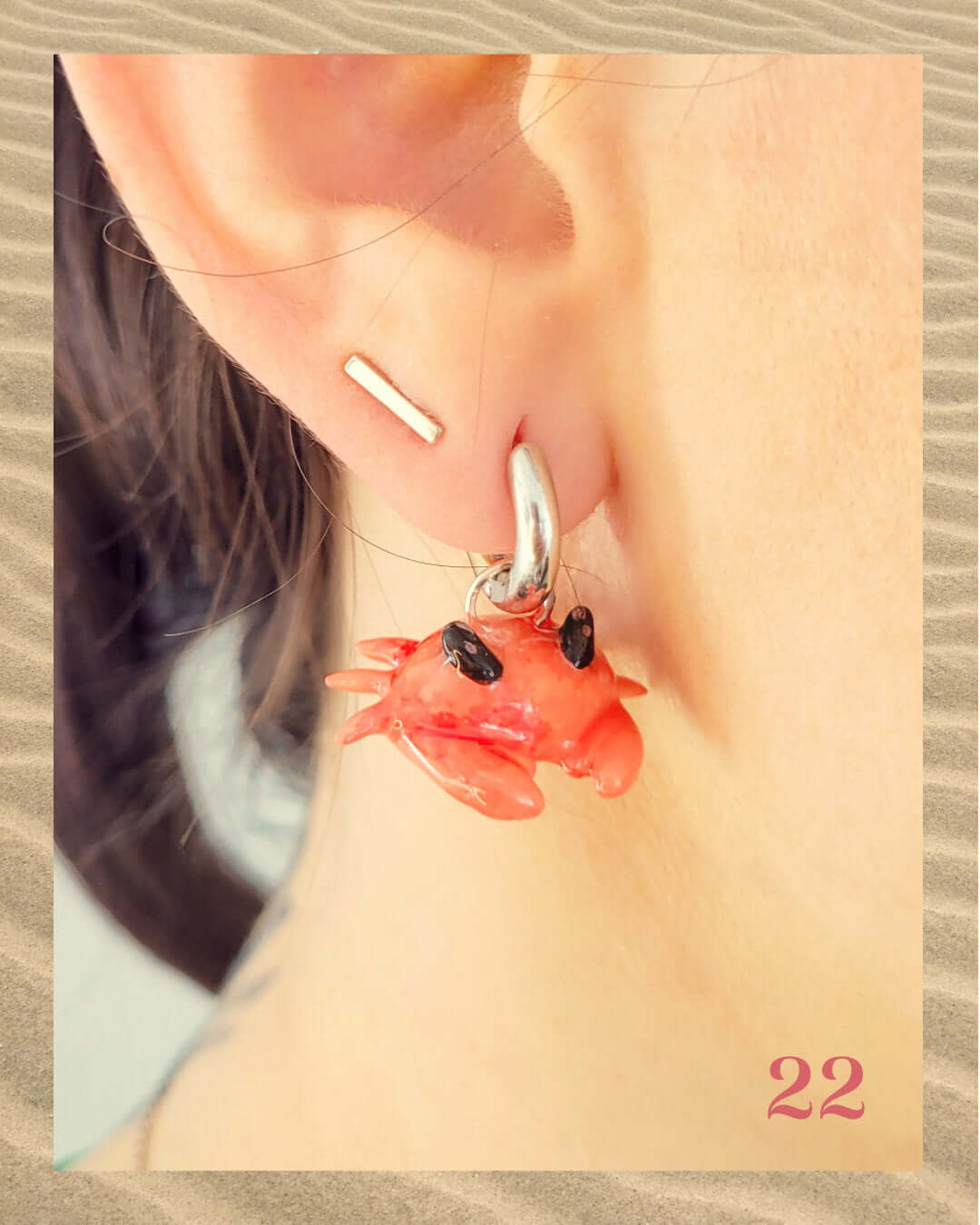 Charm amusant en forme de crabe accroché à un anneau d'oreille et porté par une femme.