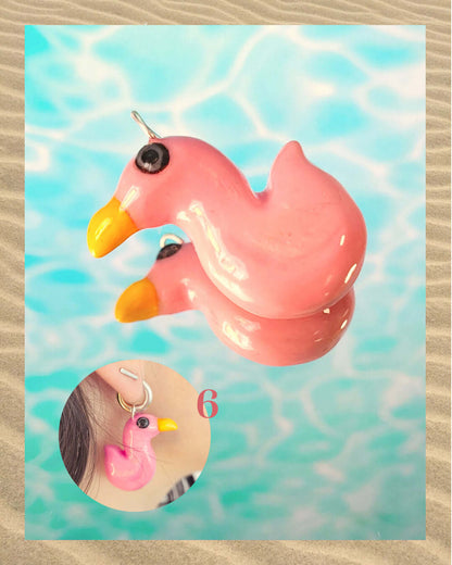 Pendentif amusant en forme de flamant rose aux reflet irisés, sur un fond aquatique faisant penser à la surface d'une piscine.