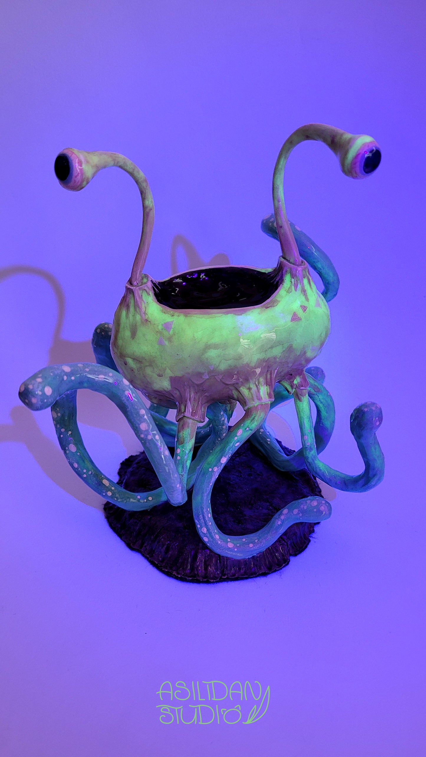 Figurine phosphorescente d'un Flumph de Donjons et Dragons, sorte de gros poulpe beige et turquoise, sous lumière UV