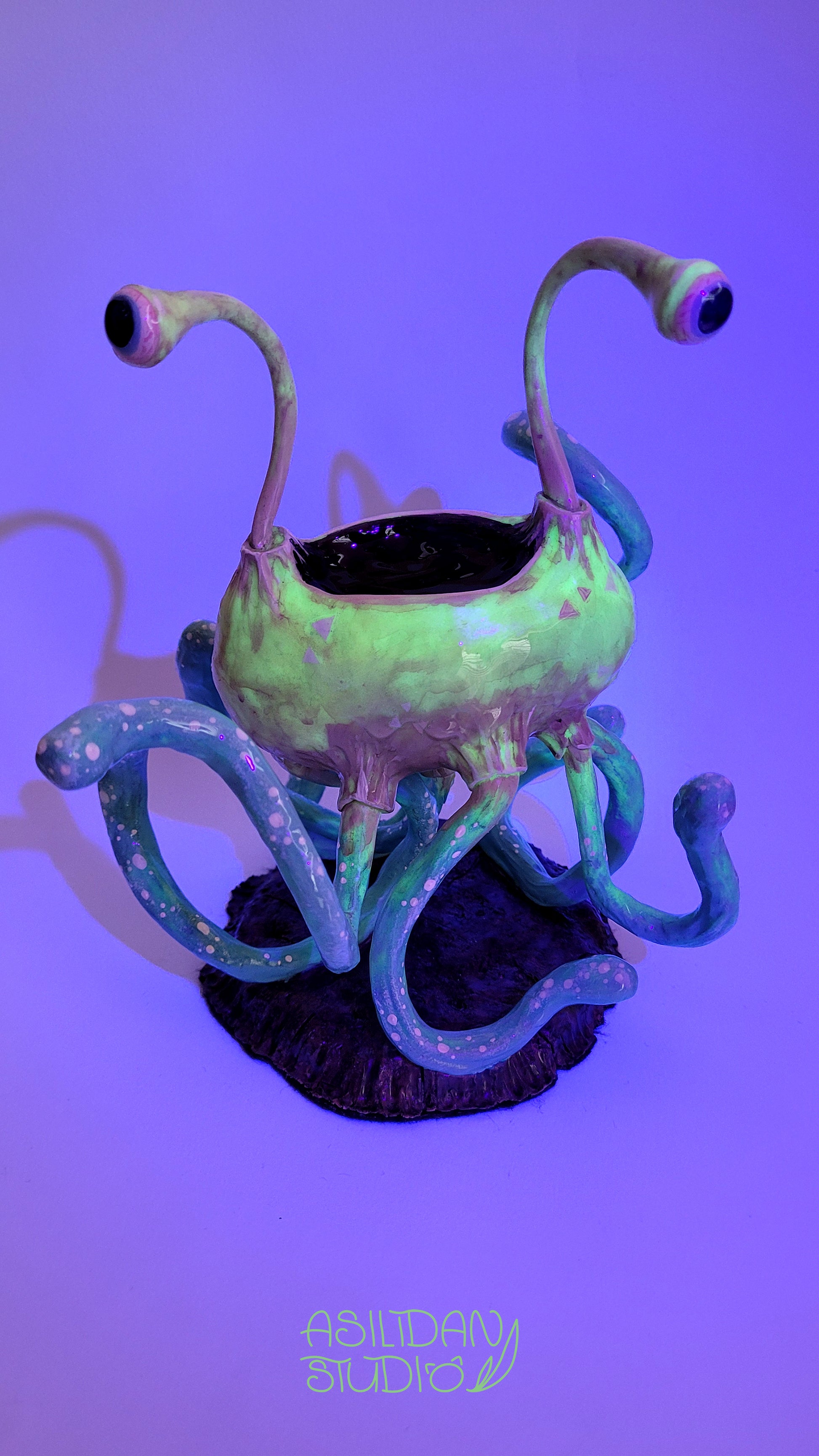 Figurine phosphorescente d'un Flumph de Donjons et Dragons, sorte de gros poulpe beige et turquoise, sous lumière UV