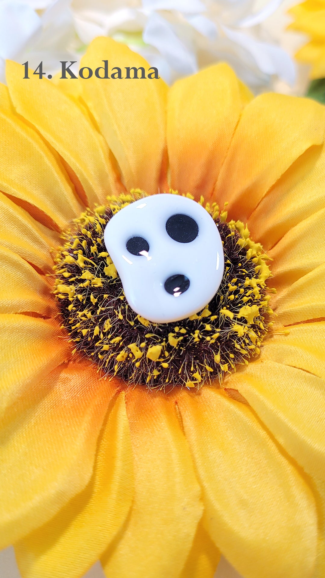 Pins en forme d'une tête de Kodama, esprit de la forêt dans Princesse Mononoké, sur un tournesol