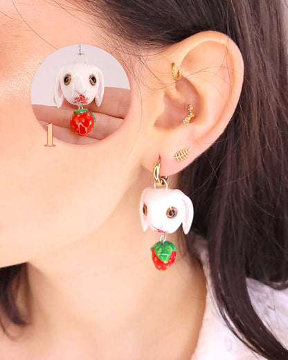 Oreille portant un charm sur un anneau en forme de lapin blanc et une fraise