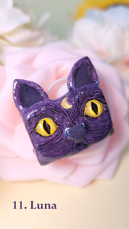 Pins en forme de tête de chat violet aux yeux dorés avec une lune sur le front, sur une rose