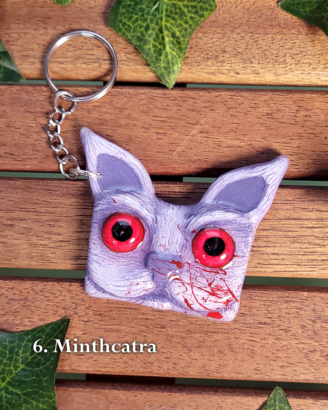 Porte-clef en forme de tête de chat mauve aux yeux rouges inspiré de Minthara de Baldur's Gate 3