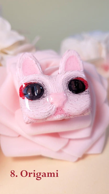 Pins en forme de tête de chat rose aux yeux noirs avec un maquillage geisha, sur une rose