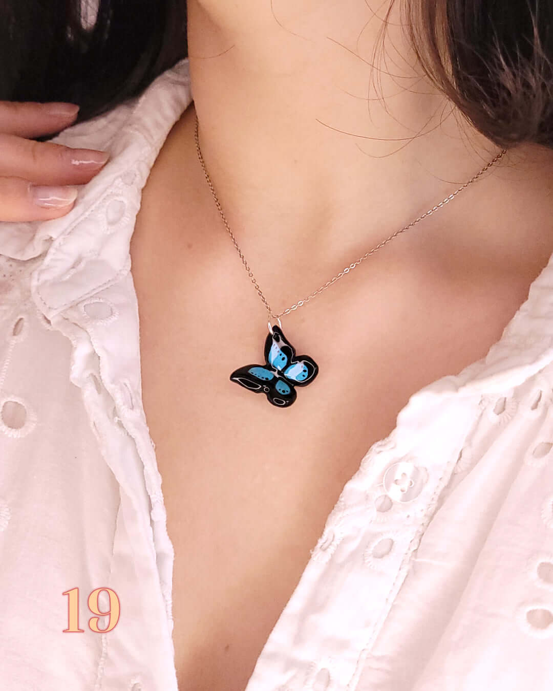 Pendentif en forme de papillon morpho bleu porté au cou d'une femme grâce à une chaînette