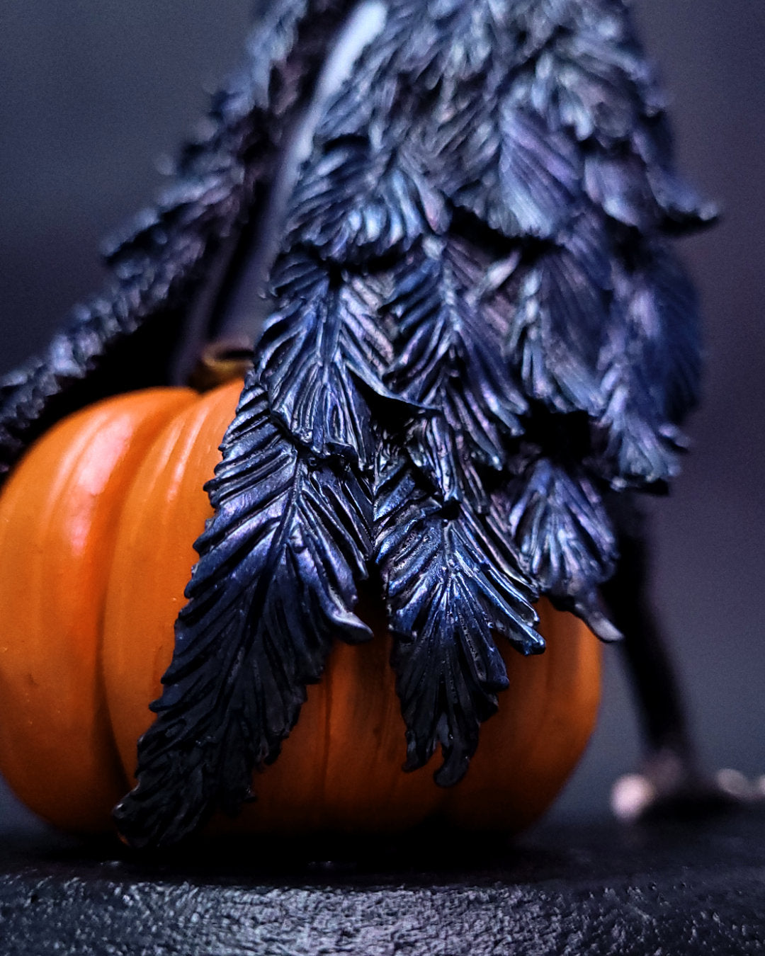 Sculpture fantasy d'une harpie mi-femme mi-corbeau assise sur une citrouille