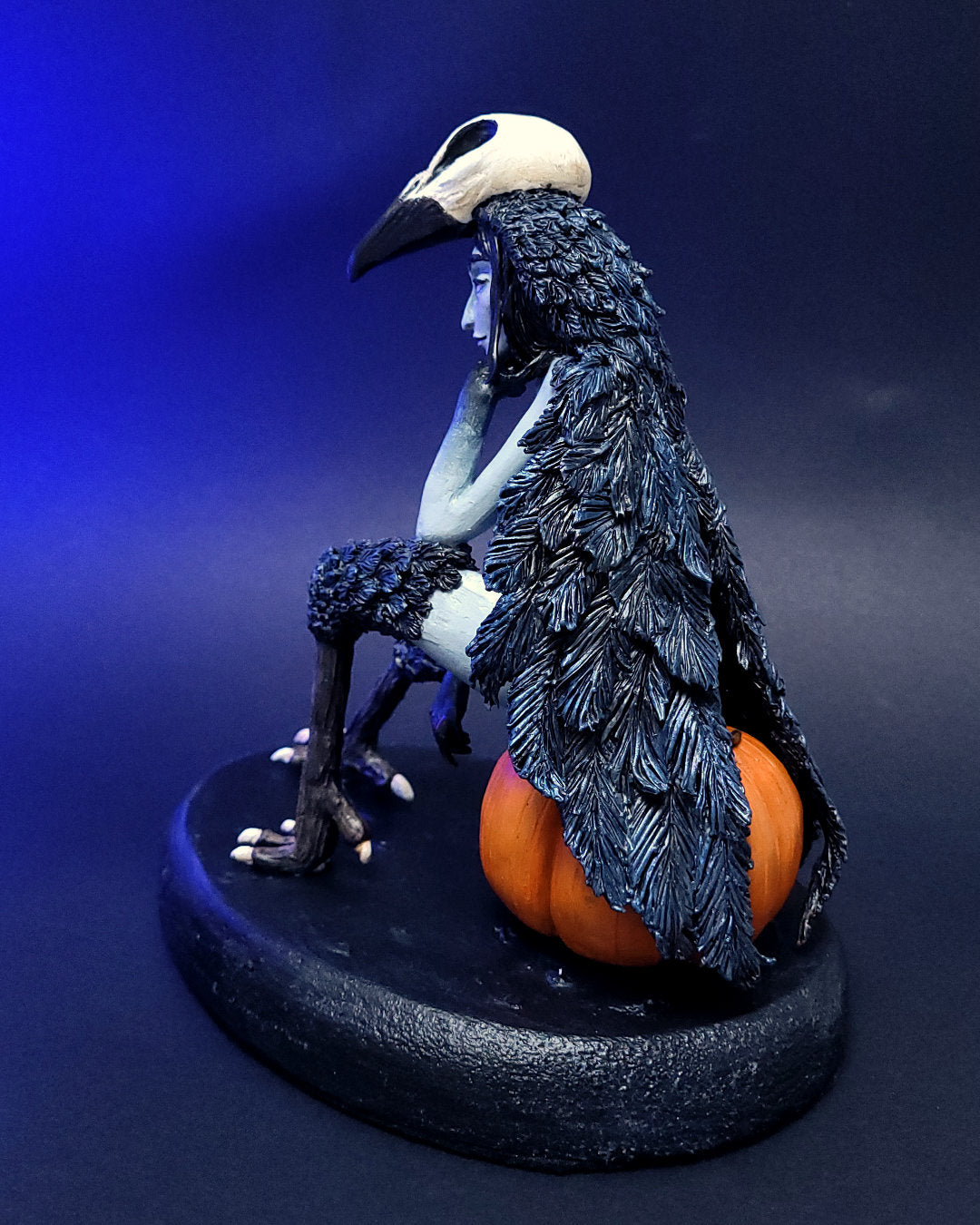 Sculpture fantasy d'une harpie mi-femme mi-corbeau assise sur une citrouille