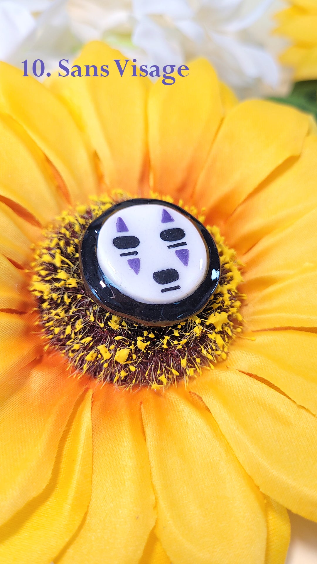 Pins en forme de la tête du Sans Visage de Chihiro, sur un tournesol