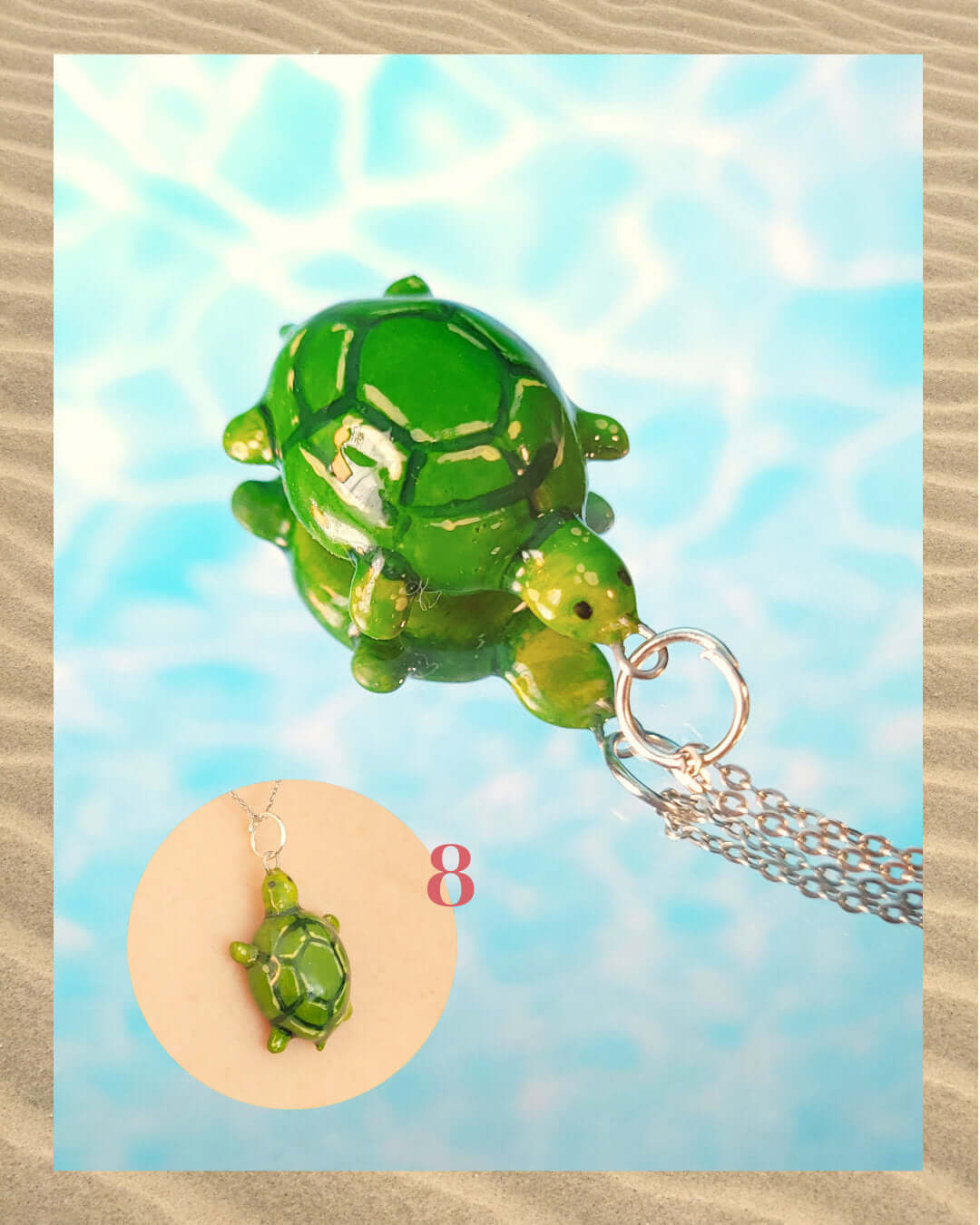 Pendentif vert en forme de tortue, sur un fond aquatique faisant penser à la surface d'une piscine et encadré de sable.