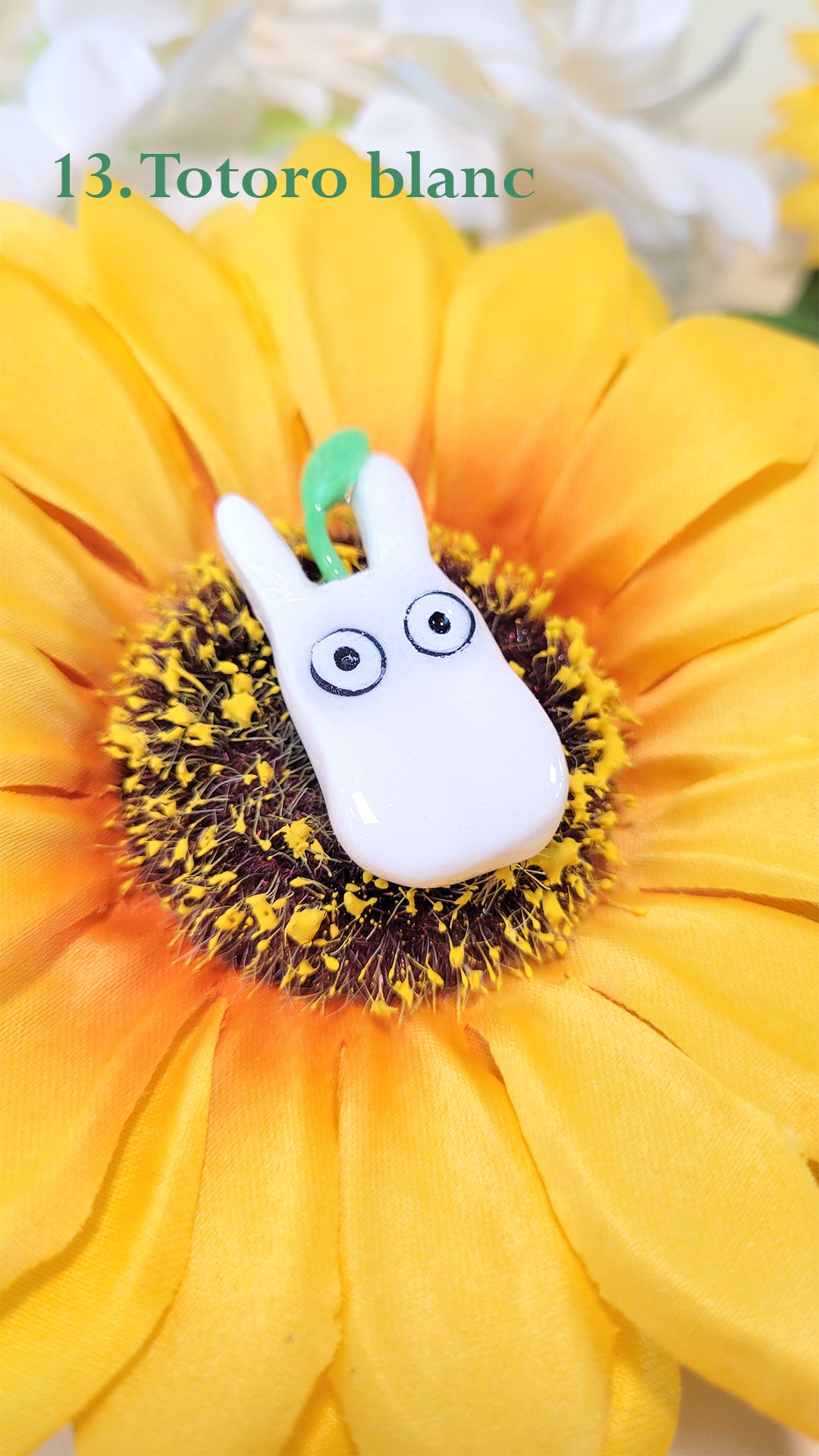 Pins en forme d'un totoro blanc avec un pousse sur la tête, sur un tournesol