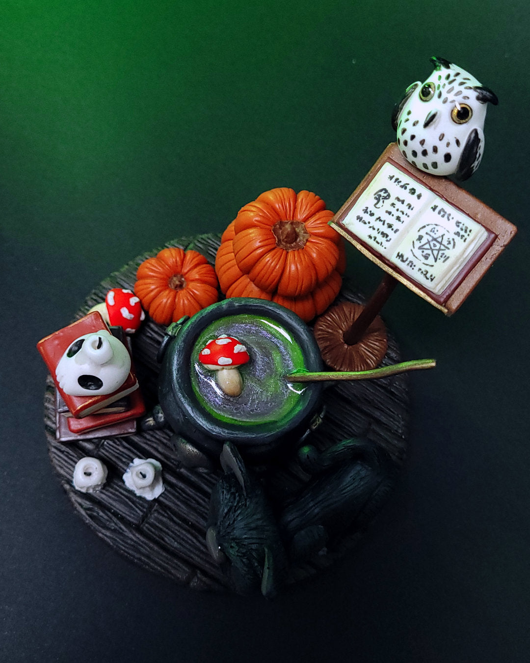 Diorama d'un atelier de potions avec un chaudron, des grimoires, un hibou, un chat noir