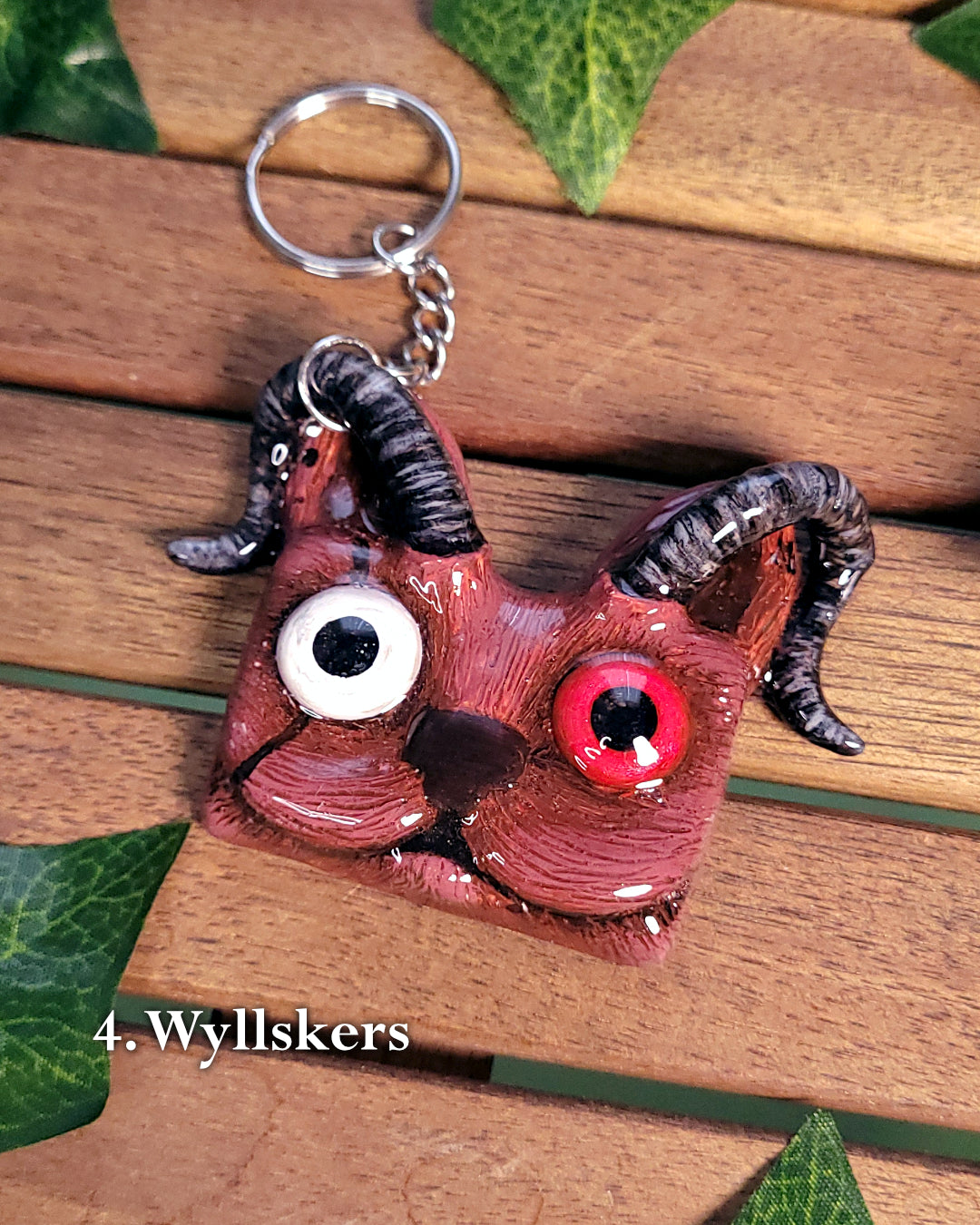 Porte-clef en forme de tête de chat rouge avec des cornes et yeux hétérochromes inspiré de Wyll de Baldur's Gate 3